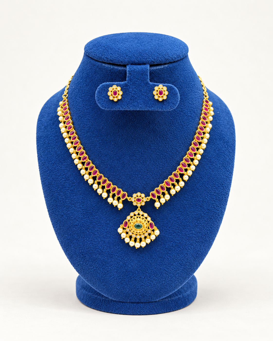 Kaveri twin row stone pendant necklace set with stud earrings in maroon on a blue velvet display stand