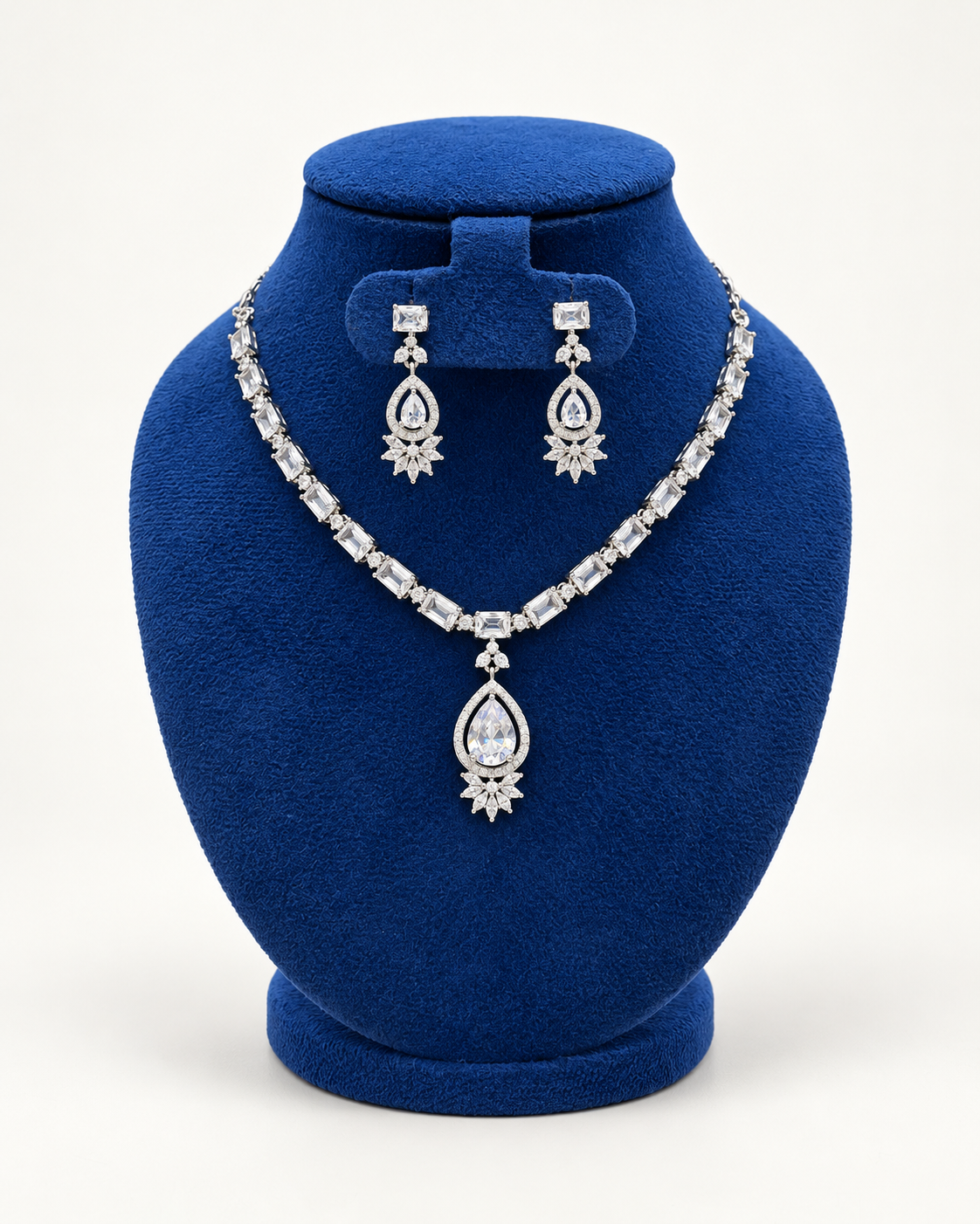 Kaveri oval stone teardrop necklace set with earrings in clear on a blue velvet display stand