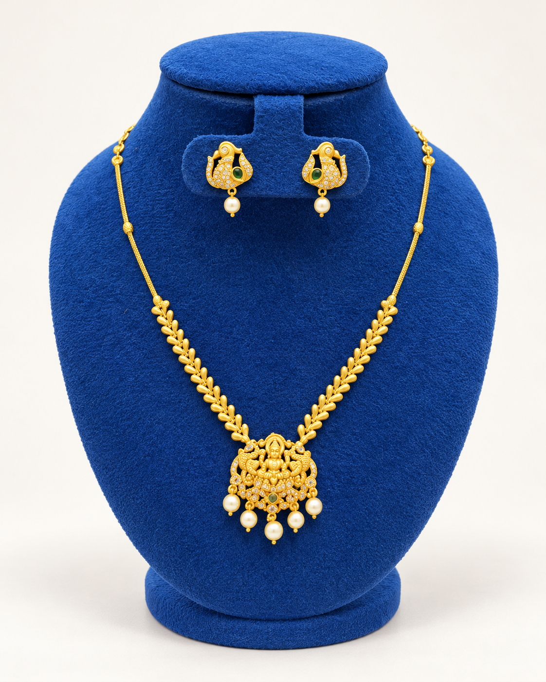 Kaveri temple pendant leaf chain necklace set with earrings in gold on a blue velvet display stand
