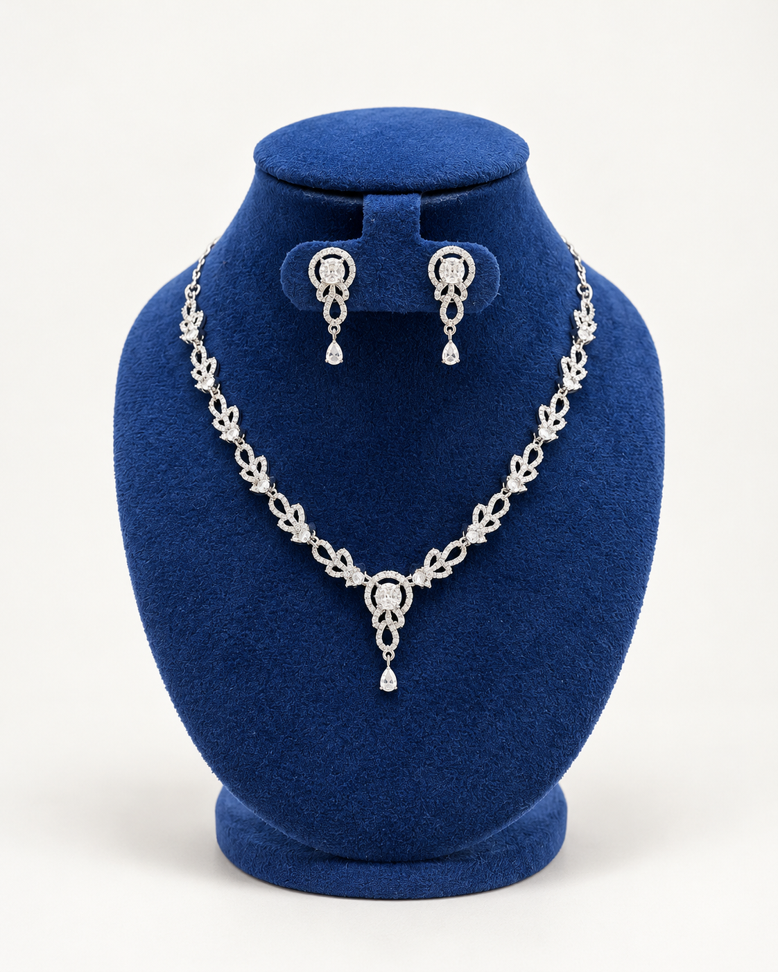Kaveri leaf garland drop necklace set with earrings in clear on a blue velvet display stand