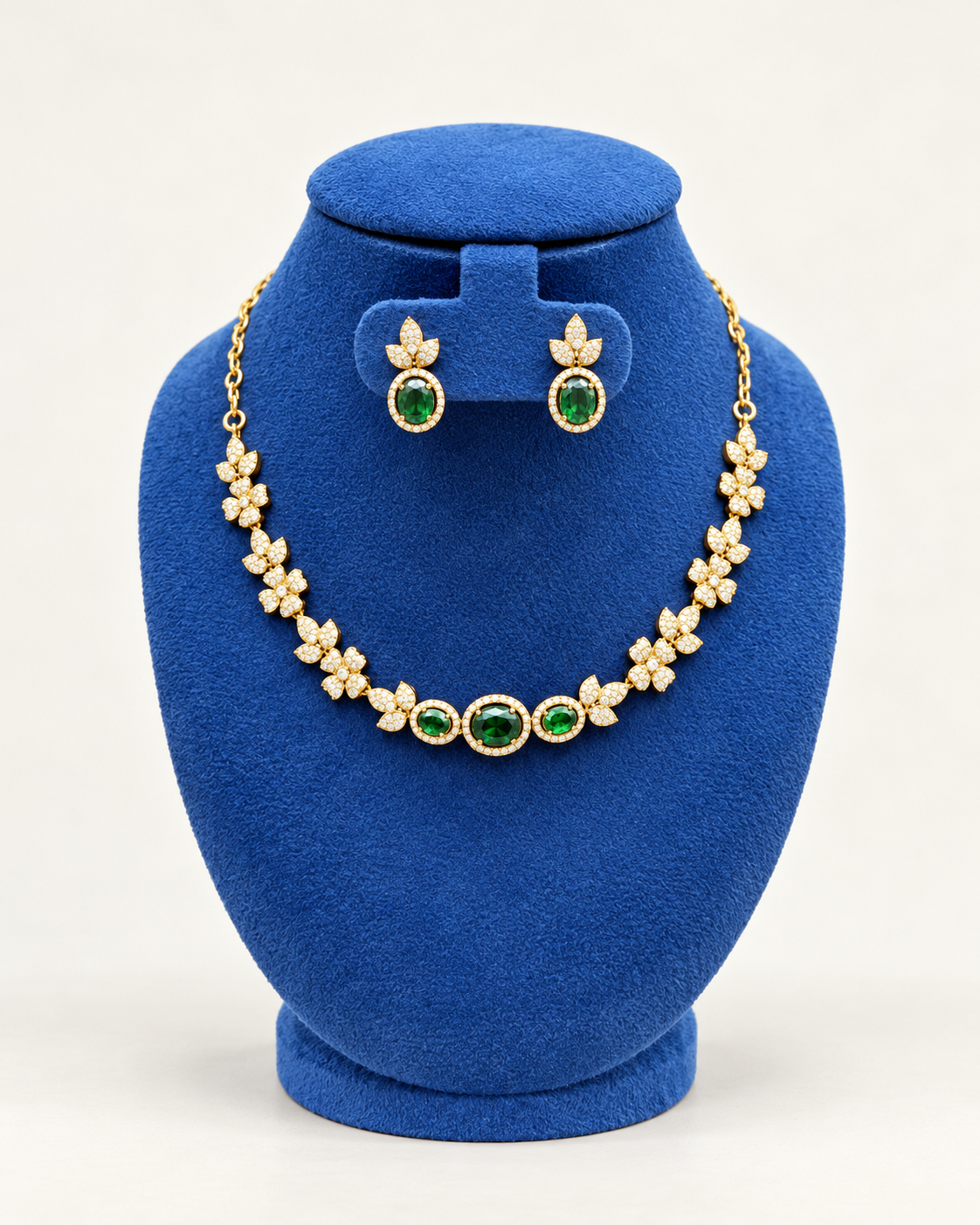 Kaveri floral three stone necklace set with earrings in green on a blue velvet display stand