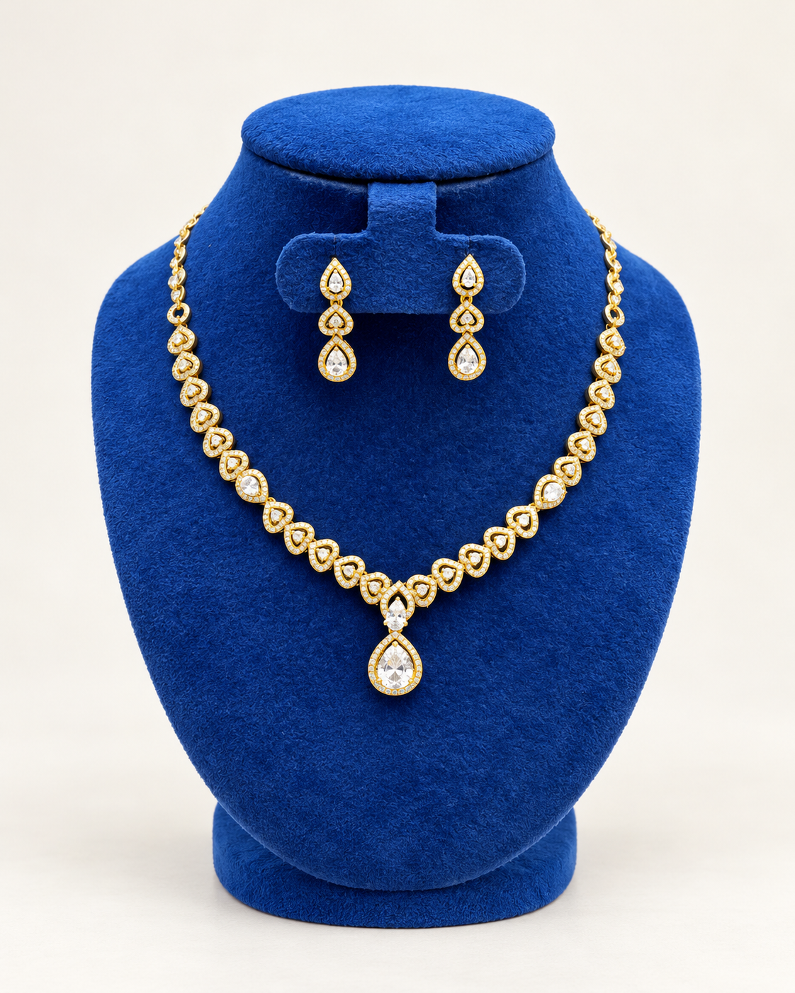 Kaveri heart garland teardrop necklace set with earrings in clear on a blue velvet display stand