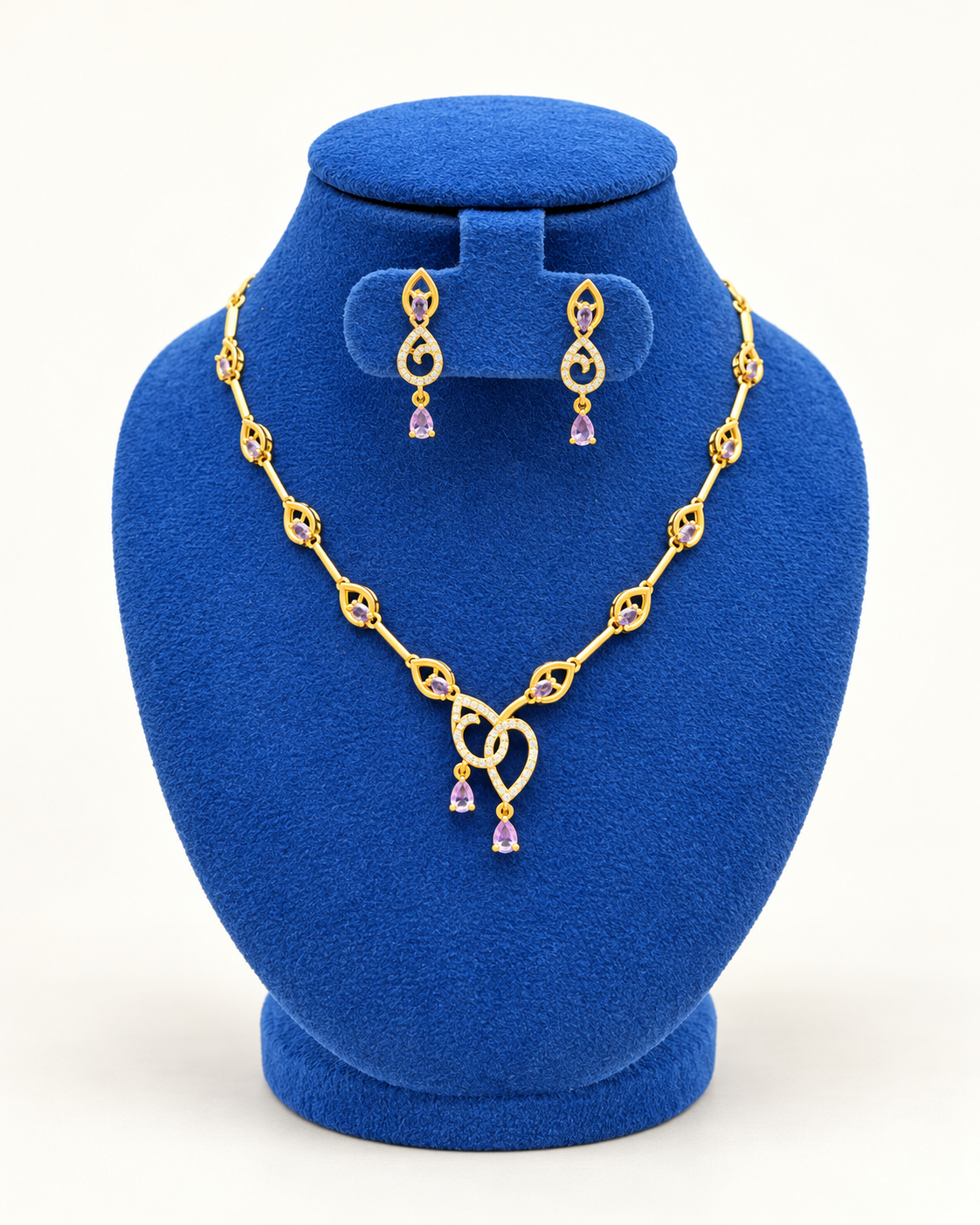 Kaveri twin loop pendant necklace set with earrings in purple on a blue velvet display stand