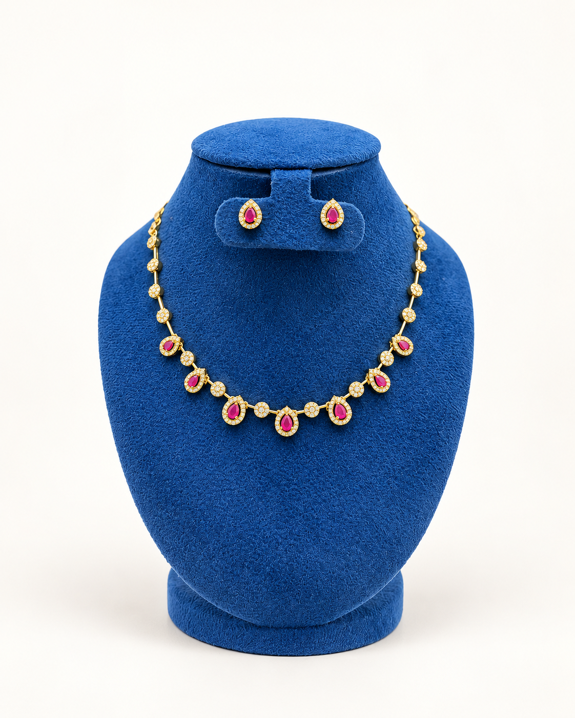 Kaveri teardrop station necklace set with stud earrings in pink on a blue velvet display stand
