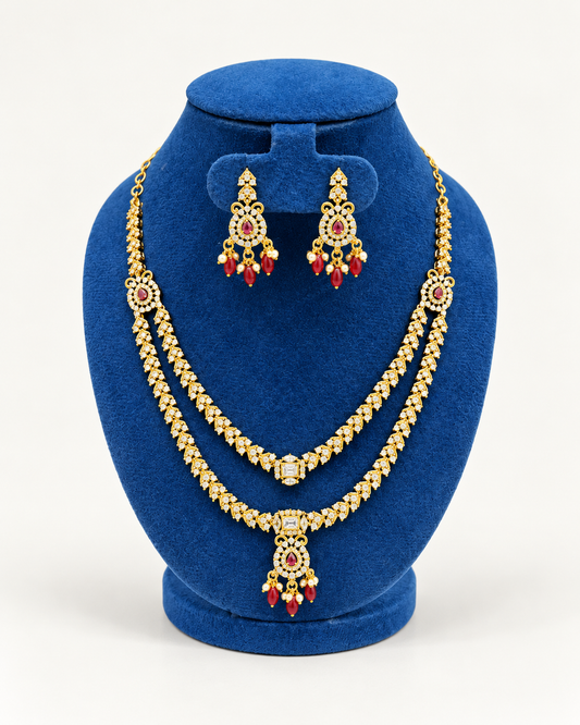 Kaveri layered stone necklace set with chandelier earrings in maroon on a blue velvet display stand