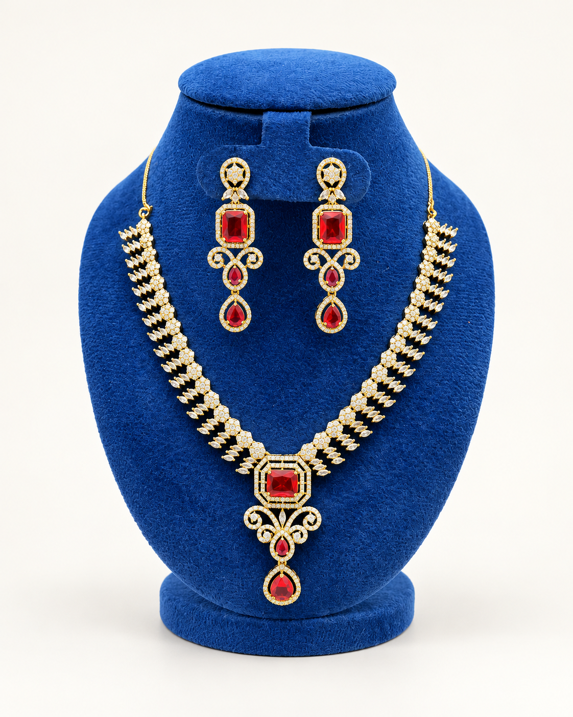 Kaveri rectangular stone cascade necklace set with earrings in maroon on a blue velvet display stand