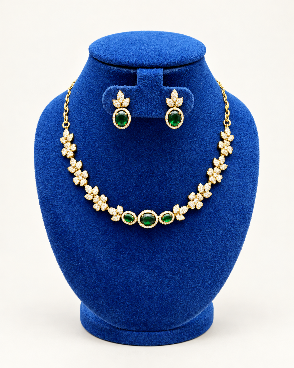 Kaveri floral three stone necklace set with earrings in green on a blue velvet display stand