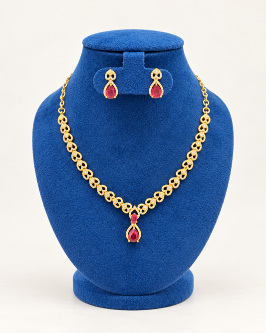 Kaveri heart link teardrop necklace set with earrings in maroon on a blue velvet display stand
