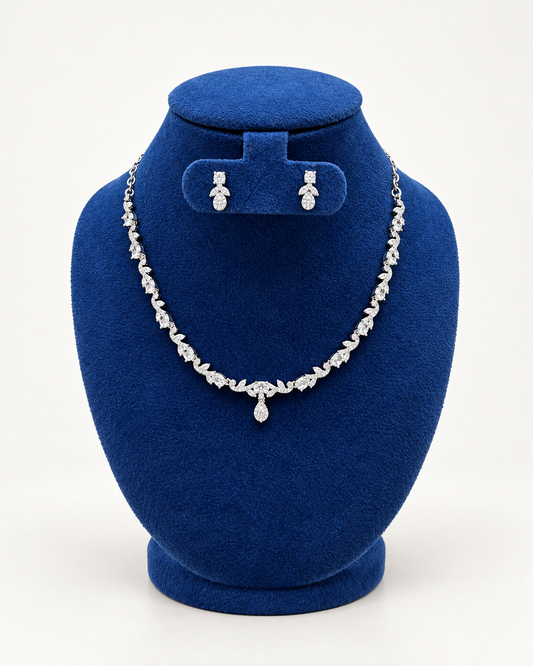 Kaveri leaf vine necklace set with petite earrings in clear on a blue velvet display stand