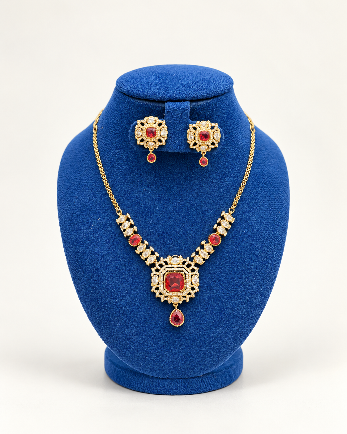 Kaveri square sunburst pendant necklace set with earrings in maroon on a blue velvet display stand