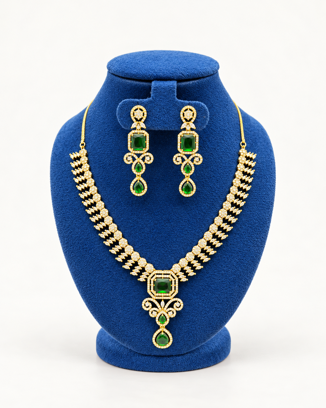 Kaveri rectangular stone cascade necklace set with earrings in green on a blue velvet display stand