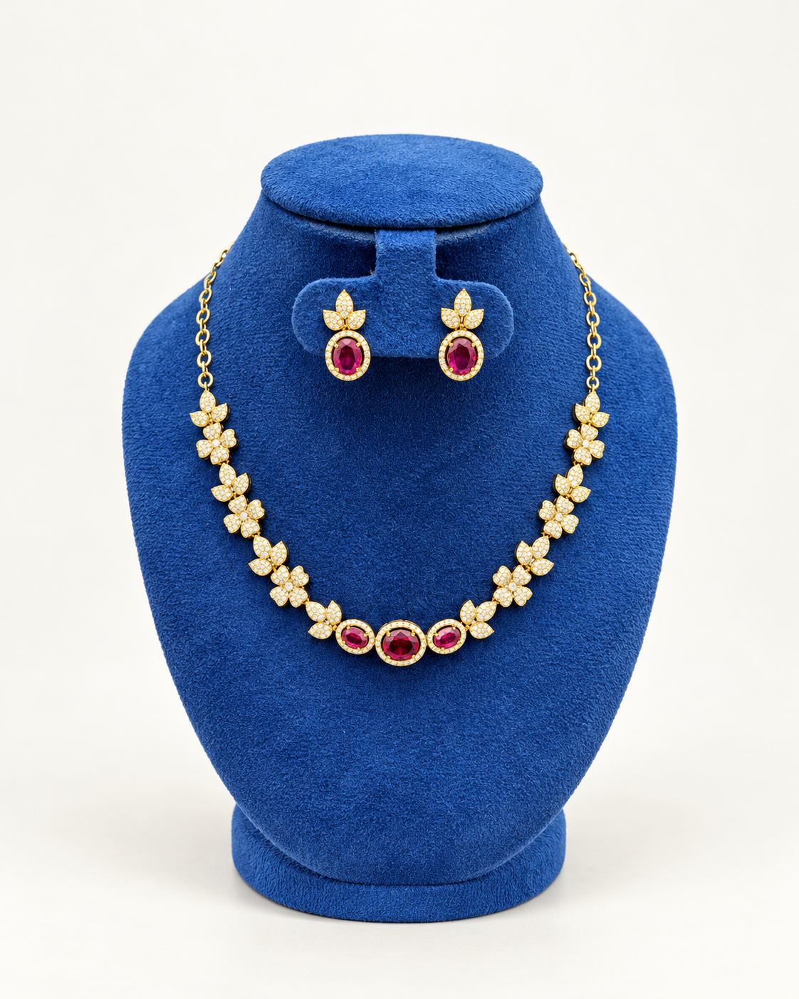 Kaveri floral three stone necklace set with earrings in maroon on a blue velvet display stand