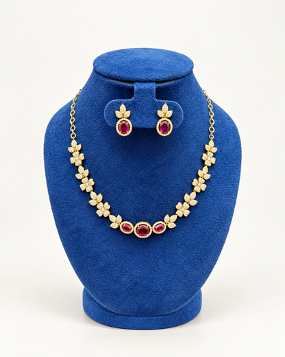 Kaveri floral three stone necklace set with earrings in maroon on a blue velvet display stand