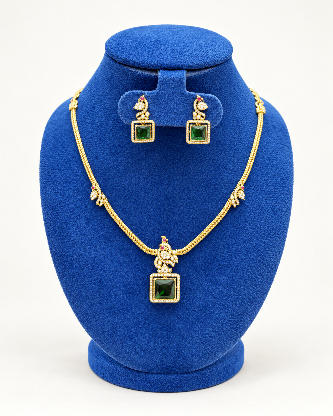 Kaveri peacock square stone necklace set with earrings in green on a blue velvet display stand