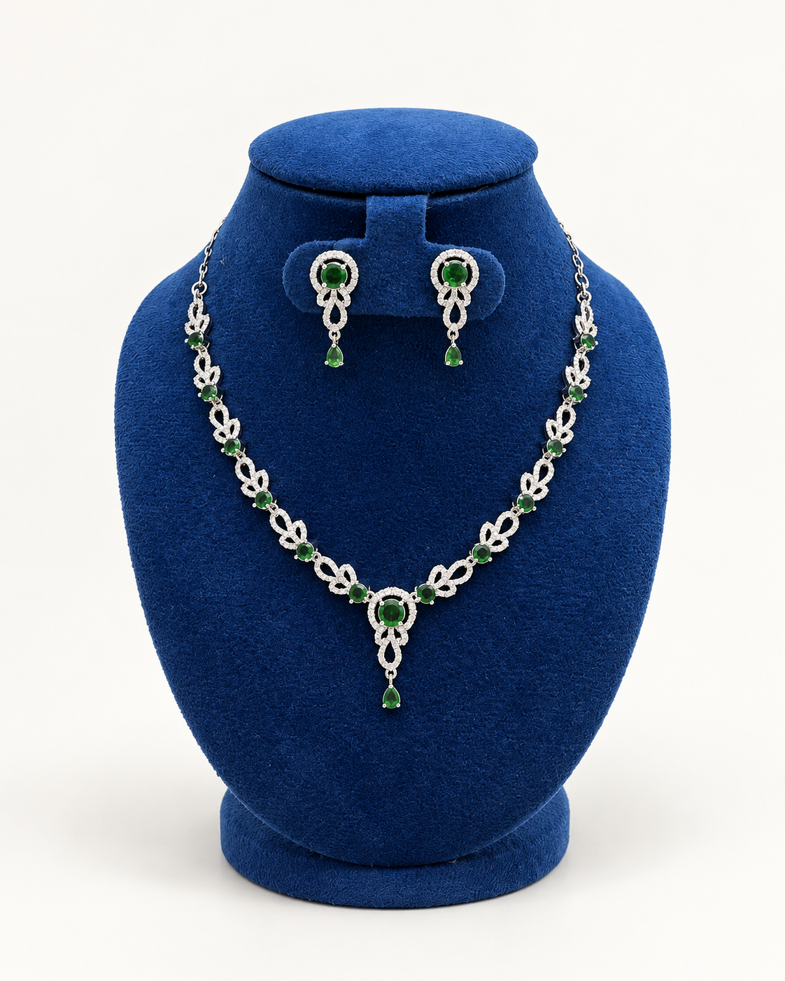 Kaveri leaf garland drop necklace set with earrings in green on a blue velvet display stand