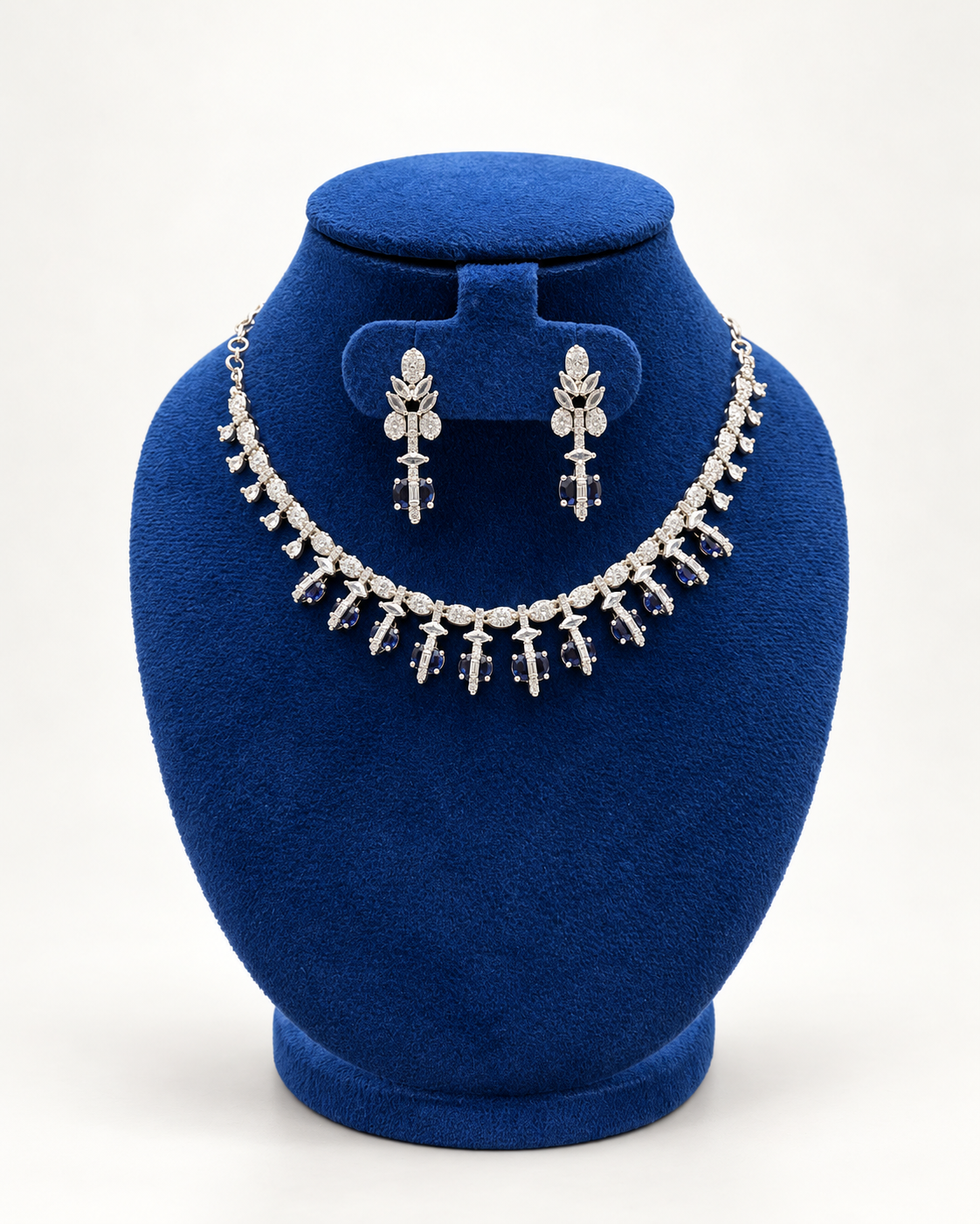 Kaveri floral fringe necklace set with earrings in clear on a blue velvet display stand