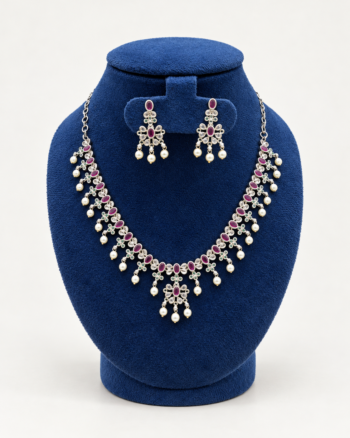 Kaveri oval stone pearl fringe necklace set with earrings in pink on a blue velvet display stand