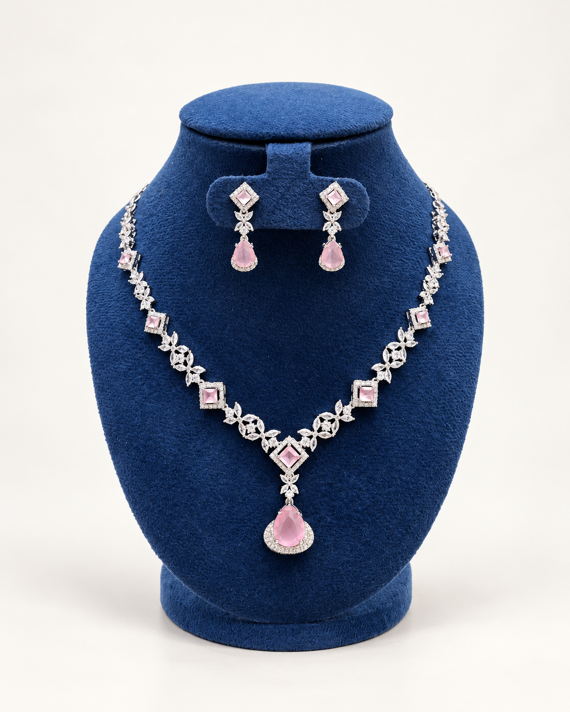 Kaveri square and leaf stone necklace set with earrings in pink on a blue velvet display stand