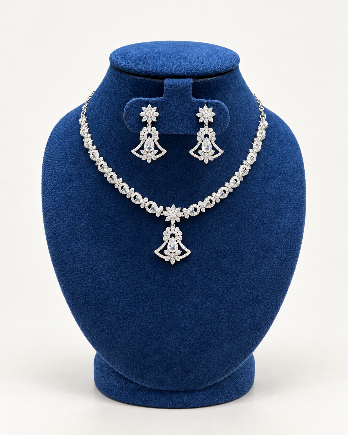 Kaveri fan pendant stone necklace set with earrings in clear on a blue velvet display stand