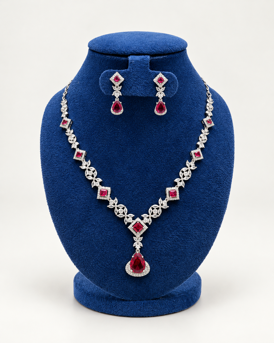 Kaveri square and leaf stone necklace set with earrings in maroon on a blue velvet display stand