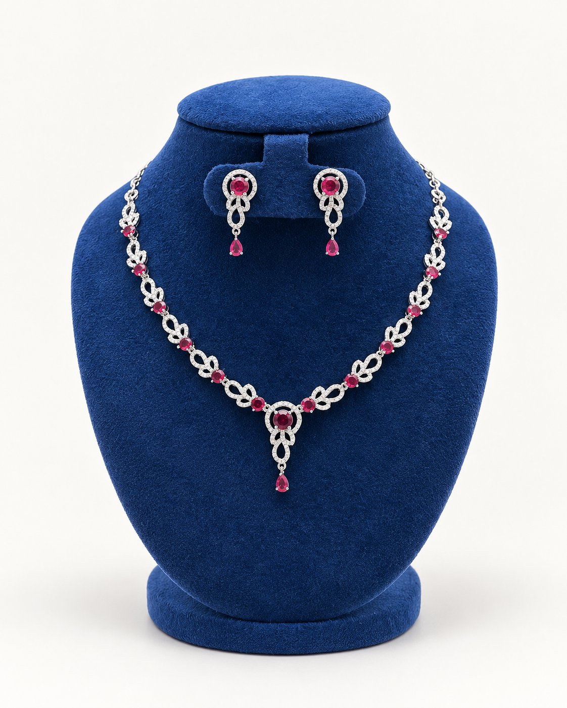 Kaveri leaf garland drop necklace set with earrings in maroon on a blue velvet display stand