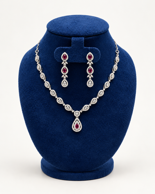 Kaveri leaf halo teardrop necklace set with earrings in maroon on a blue velvet display stand