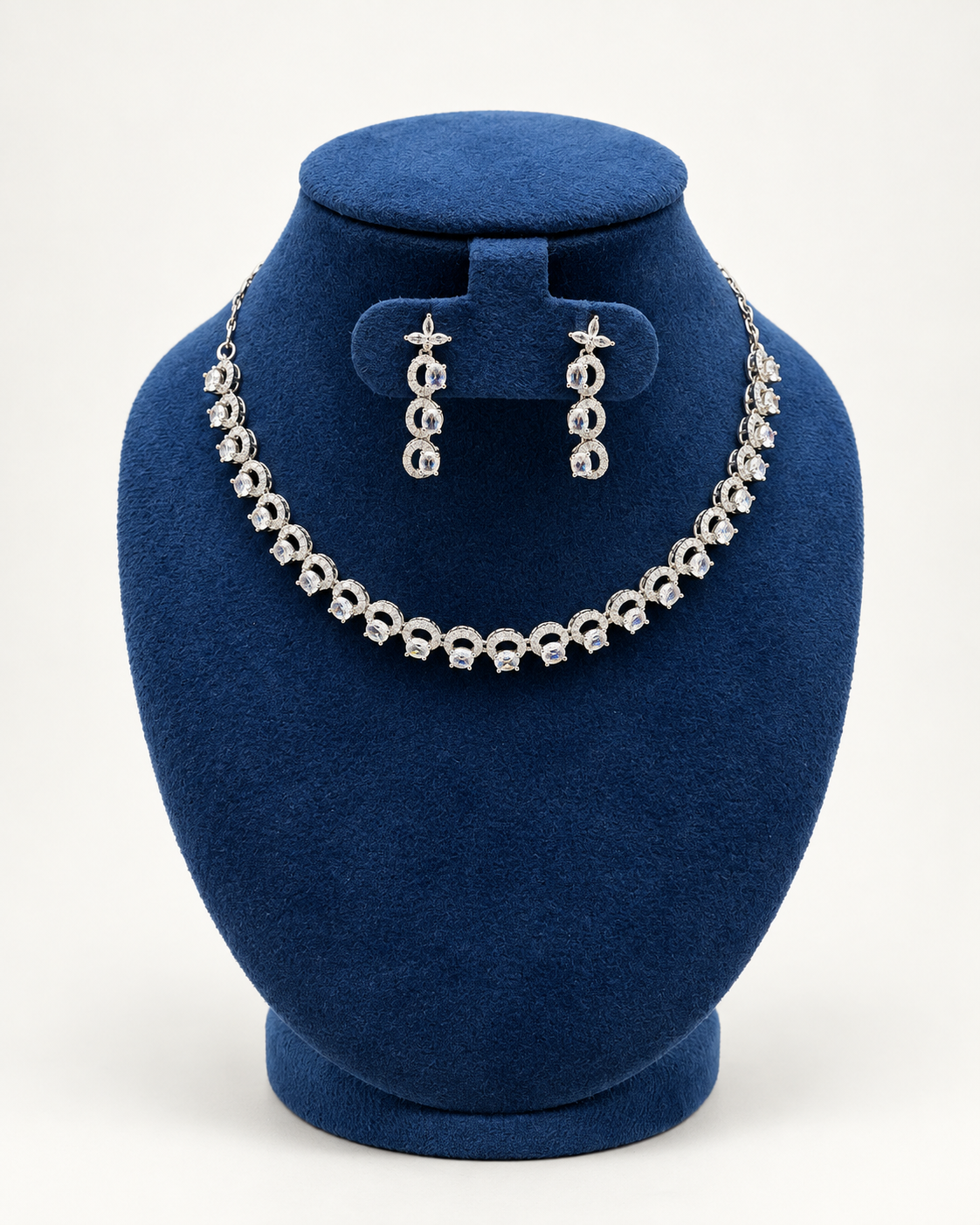 Kaveri crescent link stone necklace set with earrings in clear on a blue velvet display stand