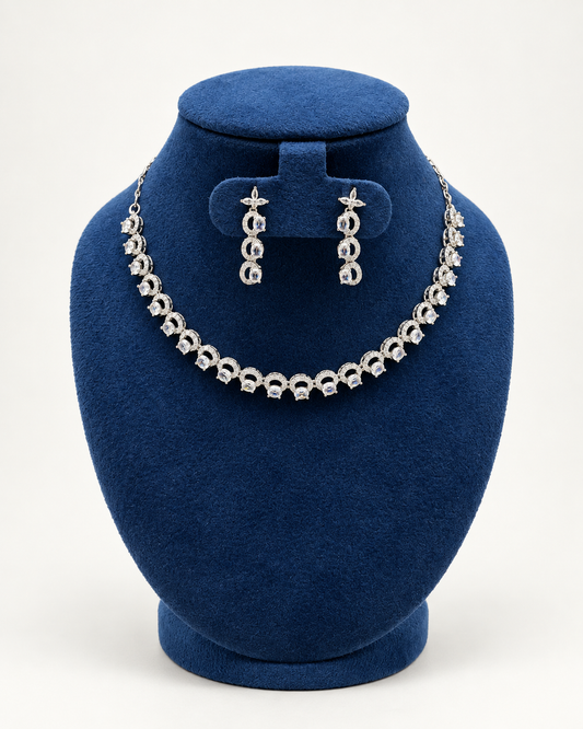 Kaveri crescent link stone necklace set with earrings in clear on a blue velvet display stand