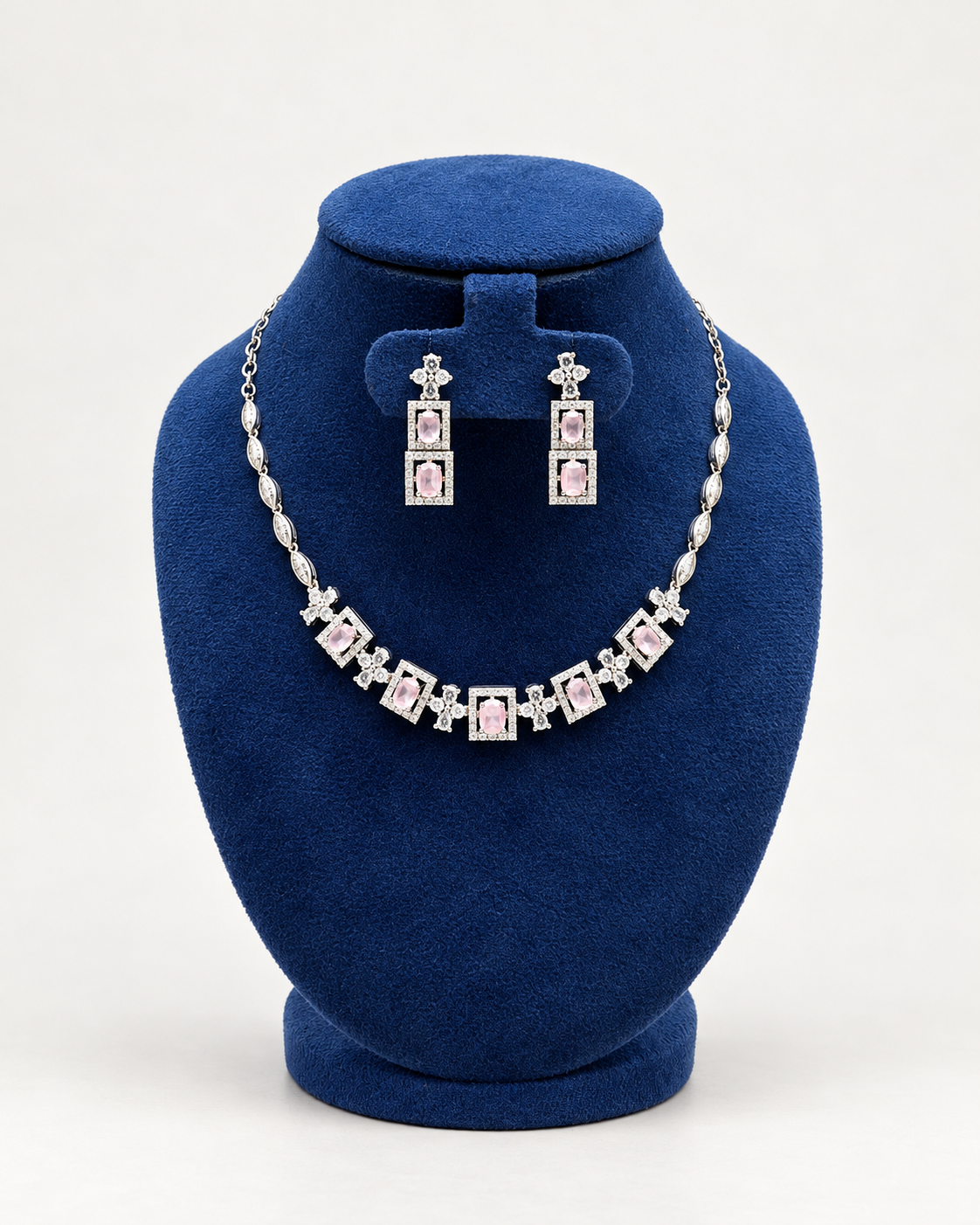 Kaveri square halo necklace set with long earrings in pink on a blue velvet display stand