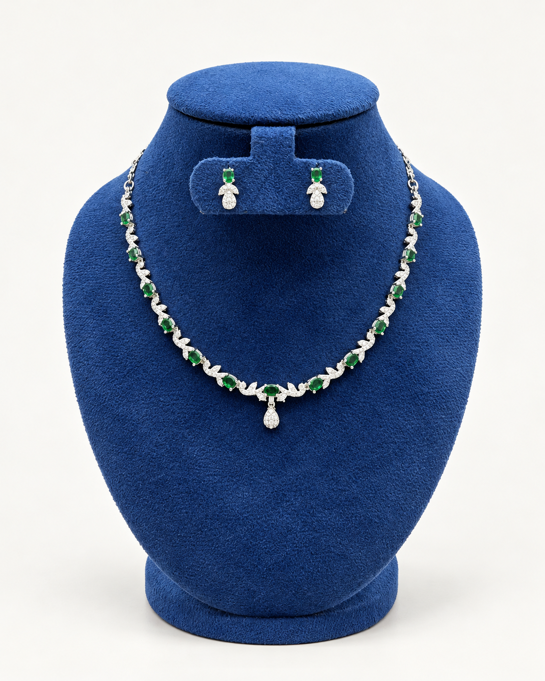 Kaveri leaf vine necklace set with petite earrings in green on a blue velvet display stand
