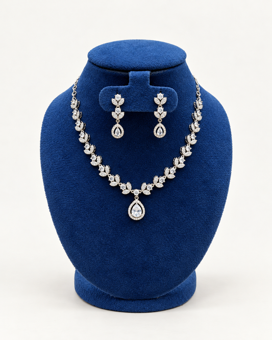 Kaveri petal cluster necklace set with drop earrings in clear on a blue velvet display stand