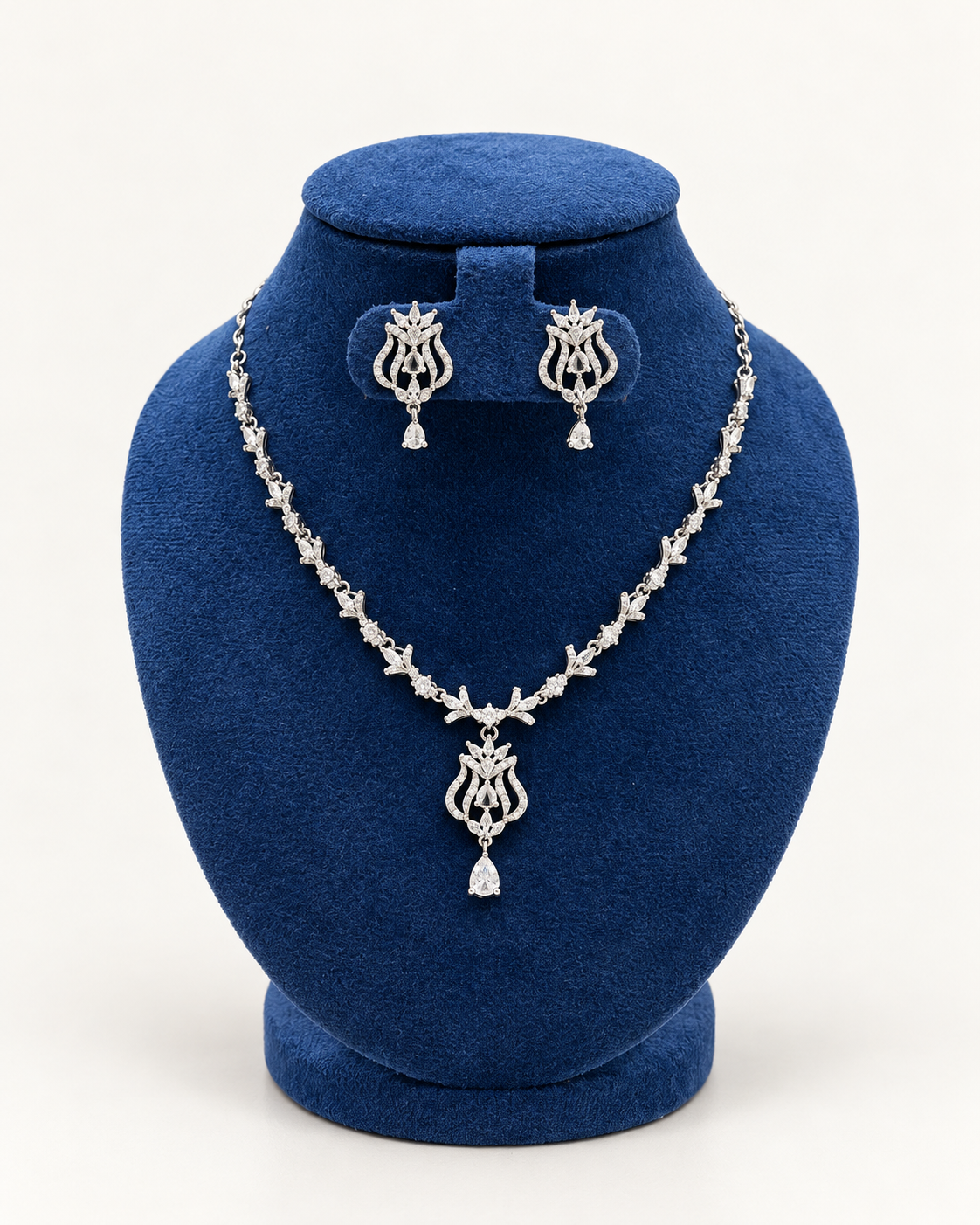 Kaveri ornate scroll pendant necklace set with earrings in clear on a blue velvet display stand