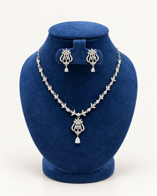 Kaveri ornate scroll pendant necklace set with earrings in clear on a blue velvet display stand