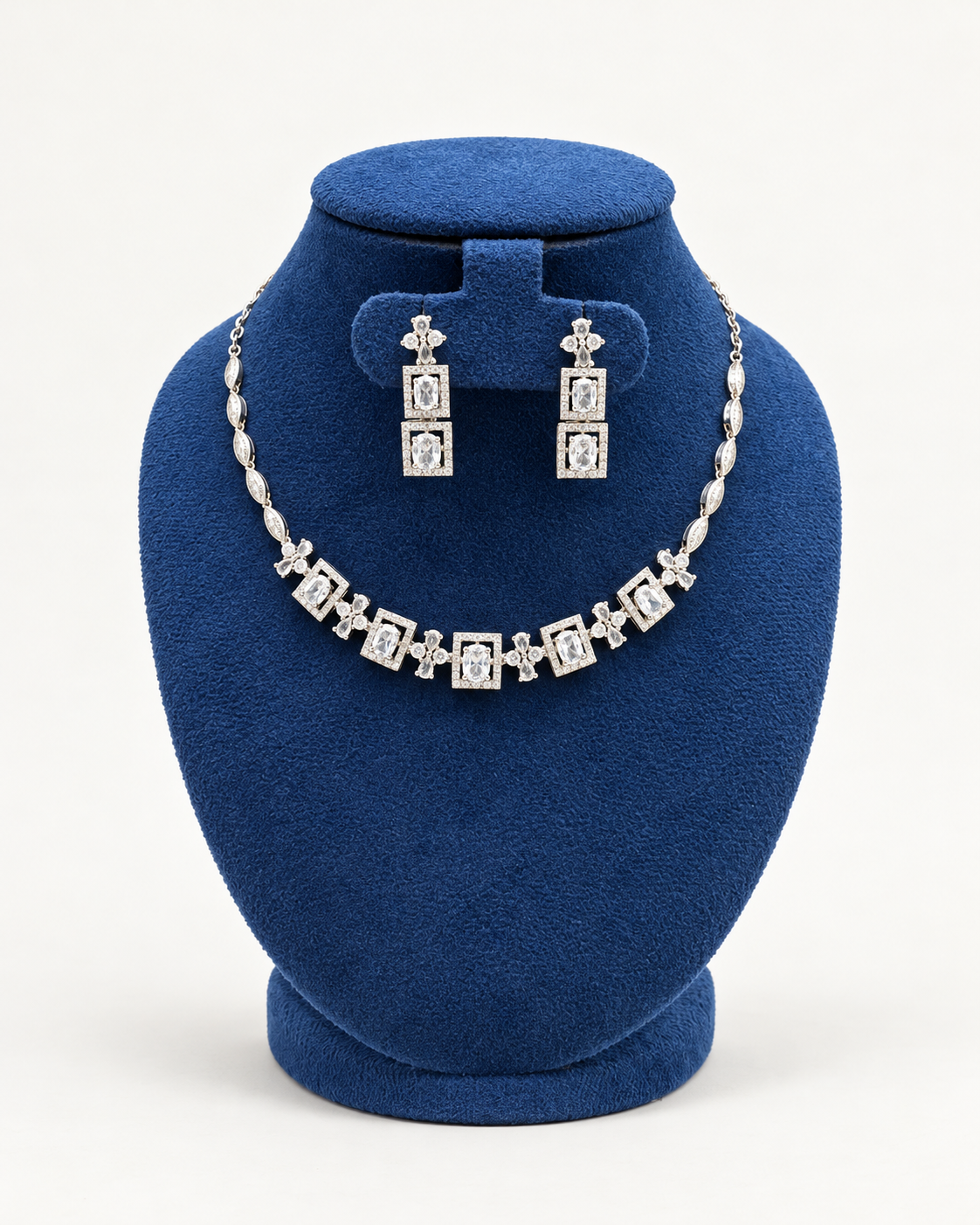 Kaveri square halo necklace set with long earrings in clear on a blue velvet display stand